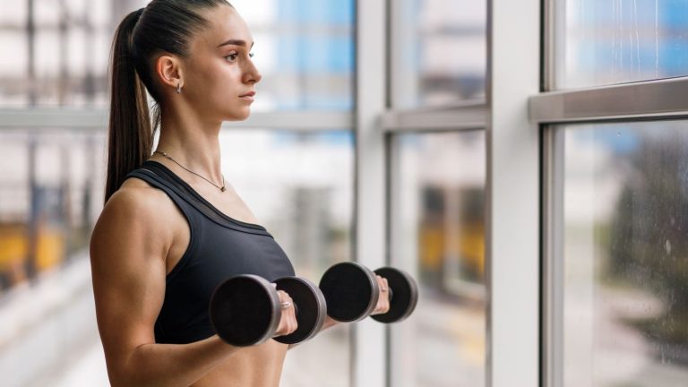 10 Exercícios de treinamento de força da parte superior do corpo que você deve tentar 1 Mulher fazendo cachos de bíceps
