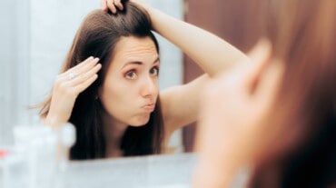 Uma mulher olhando seu cabelo branco no espelho Uma mulher olhando seu cabelo branco no espelho